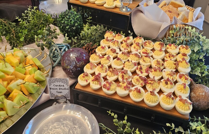 Catering in Denver: Buffet table with deviled eggs, fruit, pastries, and leafy decorations. Plates ready for serving.