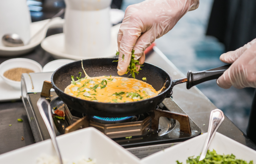 chef sprinkling ingridients in an omlette