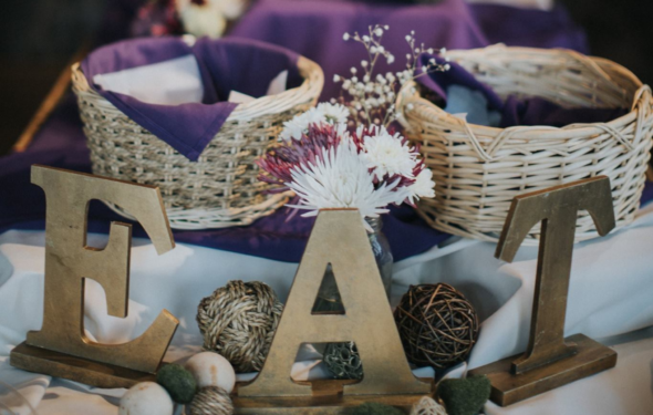 Decorative table with wicker baskets, flowers, and large letters spelling "EAT.