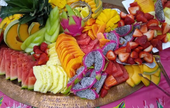 A vibrant platter of assorted fruits including melons, pineapple, strawberries, dragon fruit, and mango.