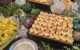 Buffet table with deviled eggs, cheese dip, melon, bread, and greenery decorations.