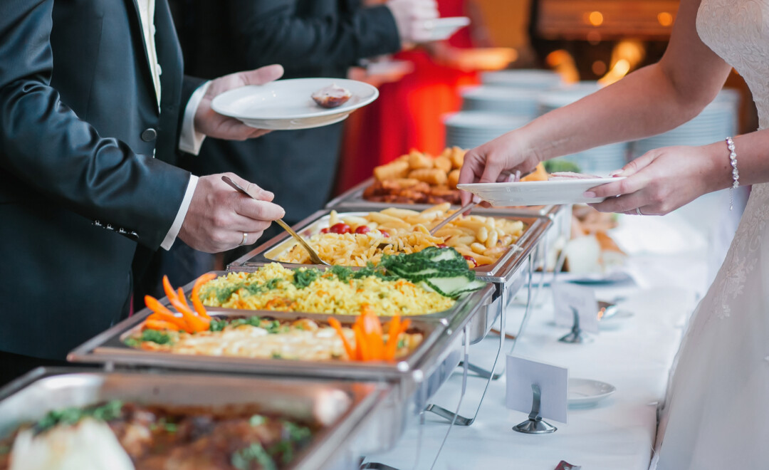 People in Denver serving buffet-style catering at a Celebration of Life, including rice, pasta, and vegetables.